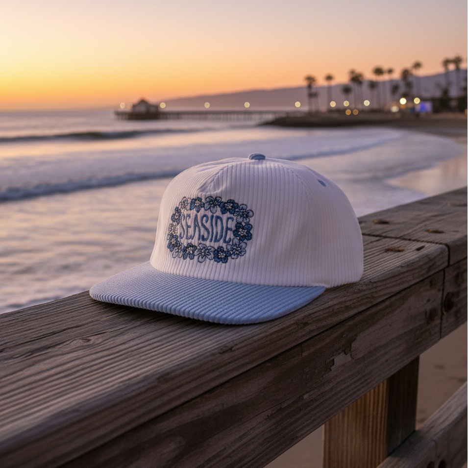 White and light blue cap with 'Seaside' floral design on a white background
