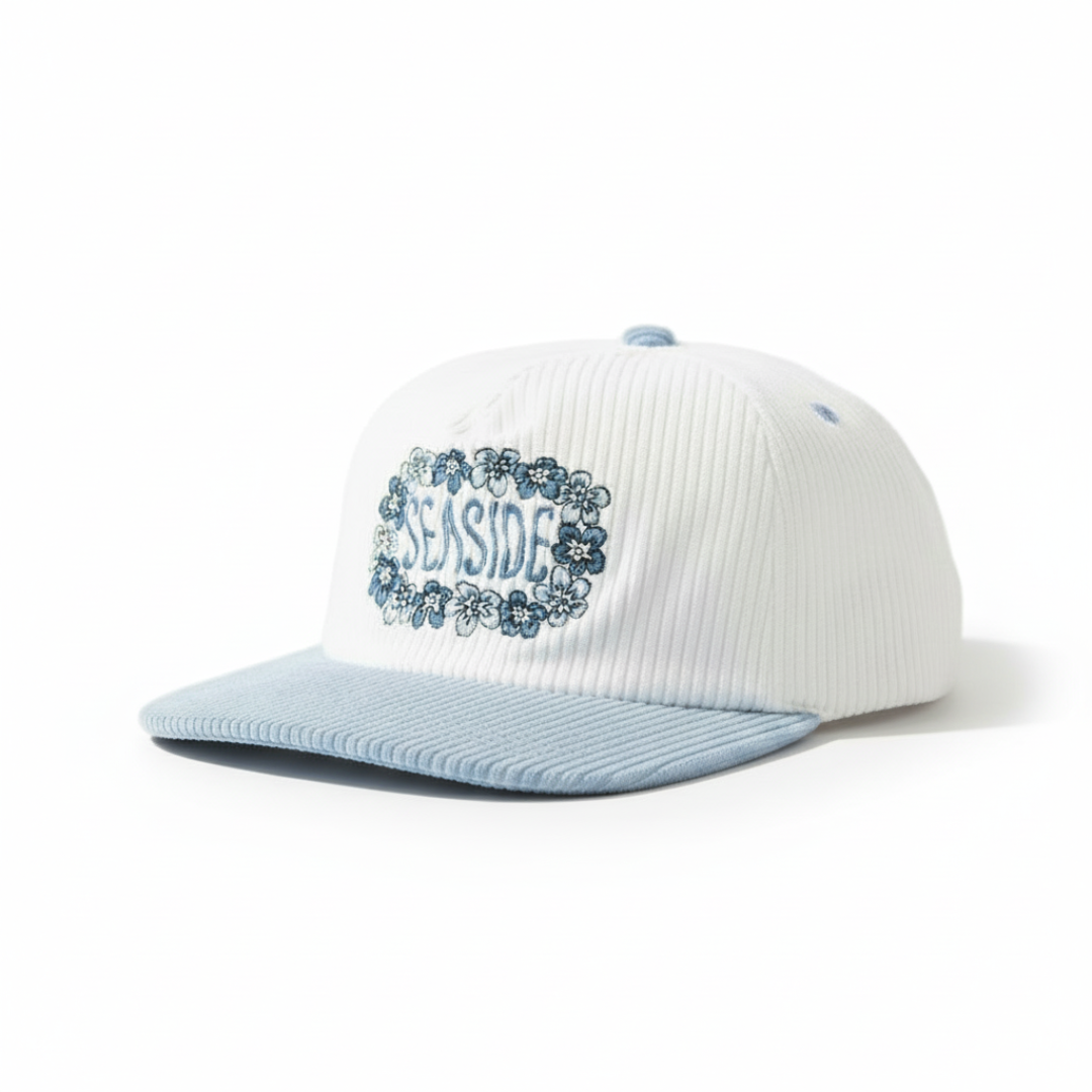White cap with blue brim and 'Seaside' text on grass