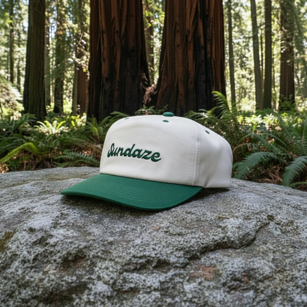 Cap with 'Sundaze' text on a rock in a forest setting