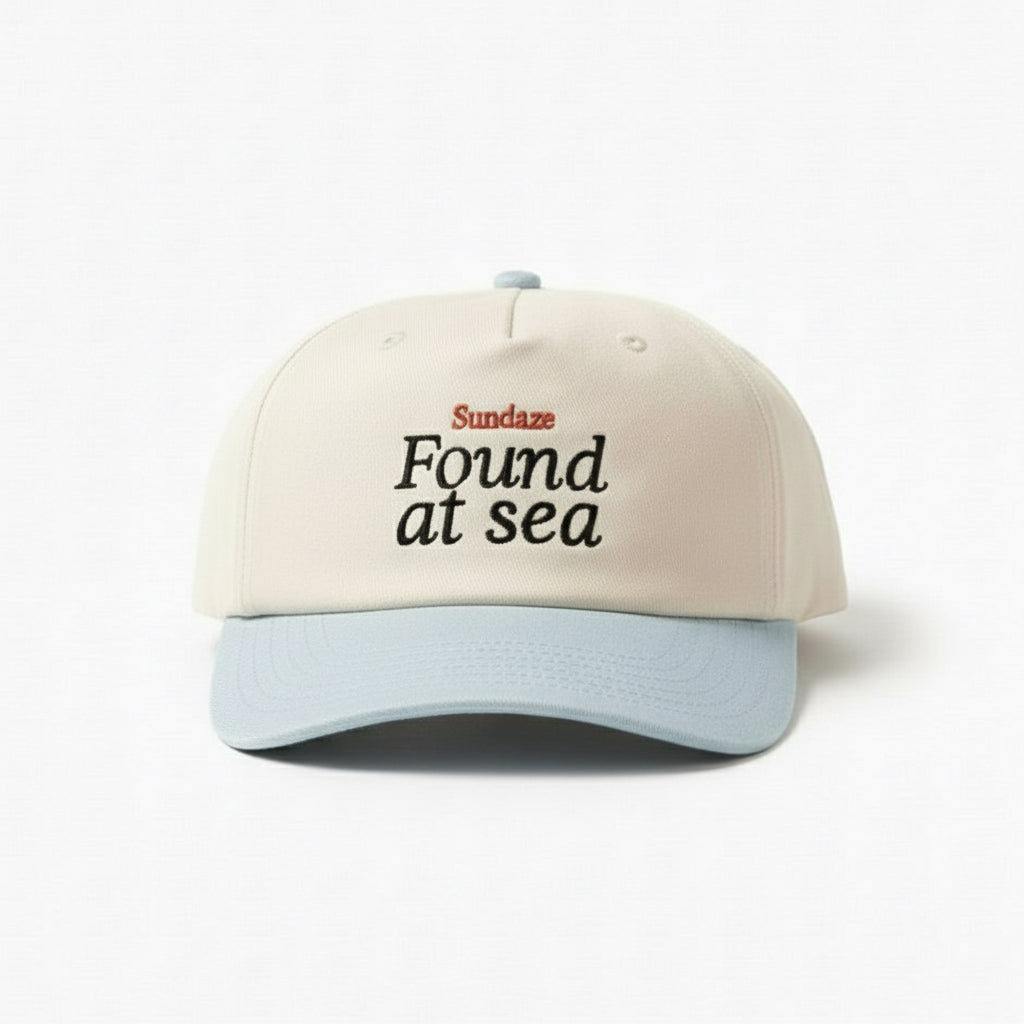 Cap with 'Found at sea' text on sand