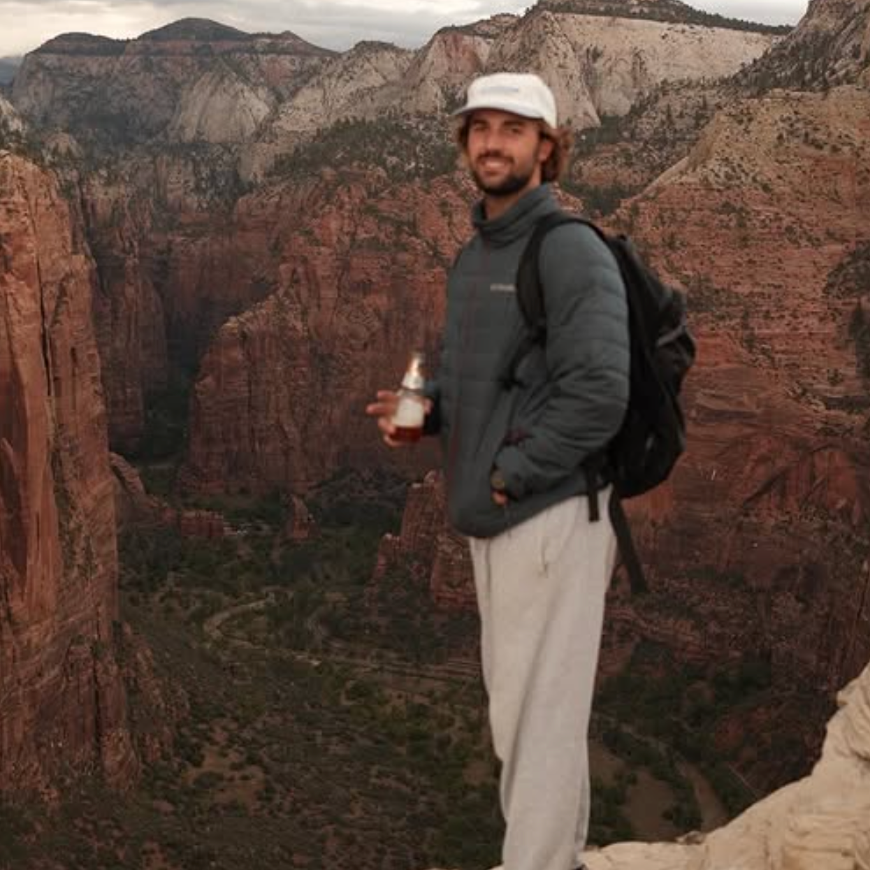 Man standing on a rocky outcrop with a scenic mountain landscape in the background